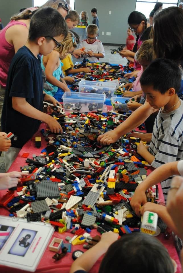 A group of young participants creating together around a large activity table