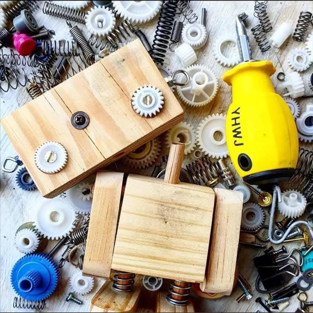 Two wooden robot builds photographed from above on a bed of salvaged gears and springs