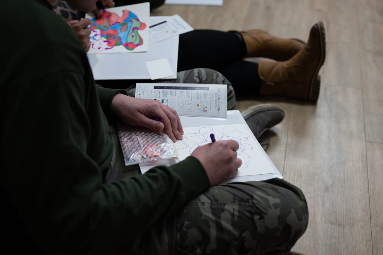 Participants seated on the floor drawing neurographic art as part of a creative team session.