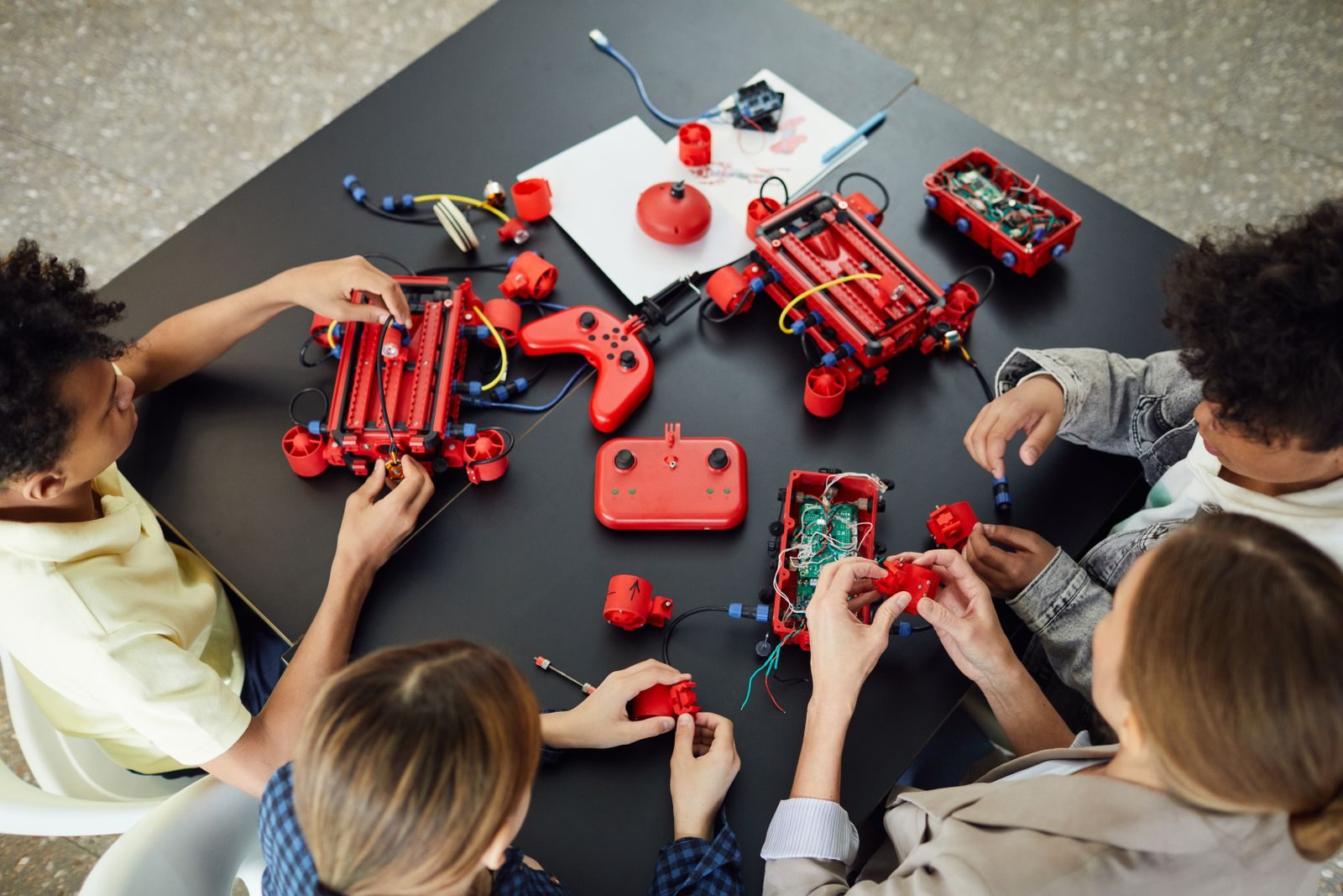 Overhead view of hands sorting motors, wheels and components across a work table